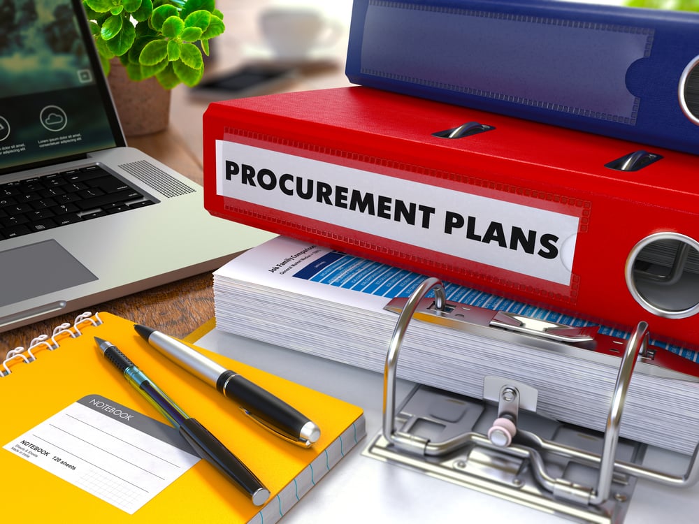 Procurement Plans on Background of Working Table with Office Supplies, Laptop, Reports. Toned Illustration. Business Concept on Blurred Background.